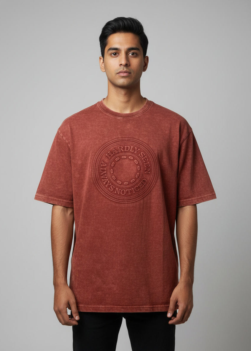 Red t-shirt with a logo on a hanger against a wooden door background